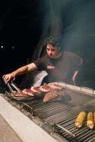 a man cooking meat and corn on a grill at Punta Mango Villas in La Periquera