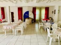 een kamer met tafels en witte stoelen en rode gordijnen bij New Verona Hotel in Wennappuwa