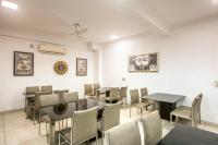 une salle à manger avec des tables et des chaises et une horloge dans l'établissement Hotel Emerald Suites & Banquet By Aura, à Noida