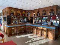 un bar avec des armoires en bois et des tabourets de bar dans l'établissement Le Grand Connétable, à Châteauneuf-de-Randon