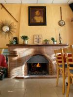 un salon avec une cheminée en briques avec un feu dans l'établissement Le Grand Connétable, à Châteauneuf-de-Randon