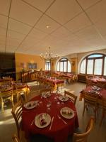 une salle à manger avec des tables rouges, des chaises et des fenêtres dans l'établissement Le Grand Connétable, à Châteauneuf-de-Randon