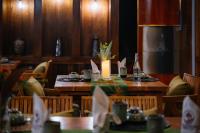 een eetkamer met houten tafels en een kaars bij An Station - Dorm & Onsen packaged in Ha Giang