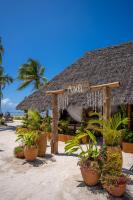 ein Restaurant am Strand mit Topfpflanzen in der Unterkunft Natural Park Villa Resort in Pingwe