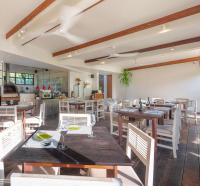 卢纳将军城L'Osteria Luxe Beachfront B&B的配有木桌和白色椅子的餐厅