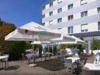 eine Gruppe von Tischen und Sonnenschirmen vor einem Gebäude in der Unterkunft Hotel Fortuna Reutlingen-Tübingen in Reutlingen