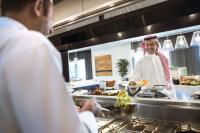 ジッダにあるCentro Shaheen Jeddah by Rotanaのキッチンに立って料理の準備をしている女性