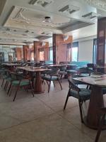 een eetkamer met tafels en stoelen en ramen bij KING'SWAY Hotel & Resort in Dūngarpur