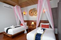 a bedroom with two beds and a clock on the wall at PingChan Koh Phangan Beachfront Resort in Thong Nai Pan Yai