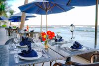 ein Tisch mit Tellern und Blumen auf einem Tisch mit Blick auf das Meer in der Unterkunft Lan Rung Beach Resort in Long Hải