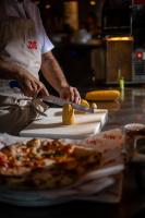 Ein Mann schneidet mit einem Messer ein Stück Pizza ab. in der Unterkunft Link Hotel & Hub By Dan Hotels in Tel Aviv