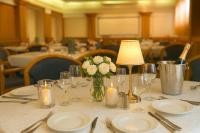 een tafel met borden en kaarsen en een vaas met bloemen bij Plaza Hotel Gyula in Gyula