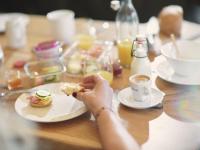 una persona che mangia un panino su un tavolo con una tazza di caffè di Boutique Apartment Sonnenhang - incl SPA-AREA a Fliess