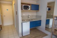 a kitchen with blue cabinets and a sink and a microwave at Spazio Marine Hotel - Guaratuba in Guaratuba