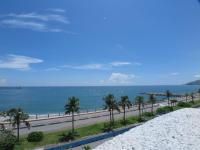 a road next to a beach with palm trees and the ocean at White Sand Homestay in Hualien City