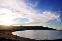 a sunset over a beach with a boat in the water at JinShan Sakura Bay Hot Spring Hotel in Jinshan