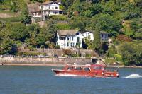a red boat in the water near a house at Hotel Villa Ruscello in Baveno