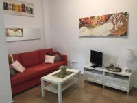 a living room with a red couch and a tv at San Juan Apartamento in Jerez de la Frontera