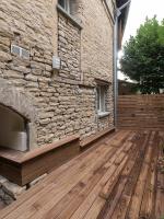 a patio with a stone wall and a wooden deck at Appart Hôtel Bourgoin in Bourgoin