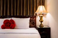 a red flower pillow on a bed next to a lamp at Han She Hotel in Taipei