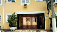 a yellow building with a gate with a dog behind it at Hotel Vila do Conde in Itu