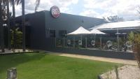 un edificio con mesas y sombrillas en un patio en Rocky Glen Hotel Motel Gladstone, en Gladstone
