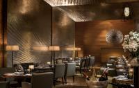 a restaurant with tables and chairs and wine bottles at Four Seasons Hotel Hong Kong in Hong Kong