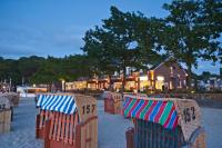 a row of chairs with umbrellas sitting on a beach at StrandHotel Seeblick, Ostseebad Heikendorf in Heikendorf