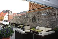 a patio with tables and chairs and a stone wall at Ringhotel Schlossberg in Neustadt