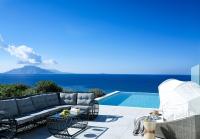 a patio with chairs and a pool and the ocean at Arpathea Villas in Foiníkion