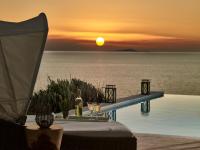 a pool with a table and a sunset over the ocean at Arpathea Villas in Foiníkion