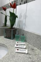 a bathroom counter with a sink and a vase with red flowers at Skala Traveling Hotel in Cuiabá