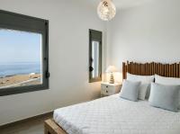 a bedroom with a bed with a view of the beach at Arpathea Villas in Foiníkion