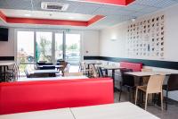 a restaurant with tables and chairs and a red bench at Ace Hôtel Caen Nord Mémorial in Caen