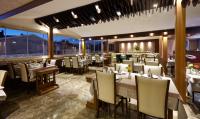 Un restaurante con mesas y sillas y un gran ventanal. en Buruciye Hotel, en Sivas