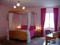a bedroom with a canopy bed with pink sheets at La Grande Mare in Saint-Benoît-des-Ondes