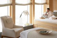 a man sitting on a bed next to a window at Four Seasons Hotel Hong Kong in Hong Kong