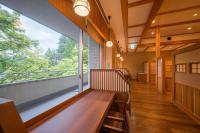 Un balcón con un banco de madera y una gran ventana. en Yumoto Kissho, en Osaki