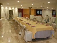 une longue table dans une pièce avec des tables et des chaises blanches dans l'établissement Hotel Fonda Neus, à Sant Sadurní dʼAnoia