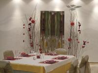 - une table avec des fleurs rouges dans une pièce dans l'établissement Hotel Fonda Neus, à Sant Sadurní dʼAnoia