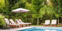 a group of chairs and an umbrella next to a pool at Lares De Chacras in Chacras de Coria