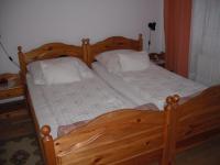 una cama de madera con 2 almohadas blancas. en Aba és Andrea Apartmanok, en Sárvár