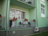 Casa verde con balcón con sillas y ventana en Aba és Andrea Apartmanok, en Sárvár
