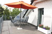 a table and chairs with an umbrella on a deck at Pension Landhaus Teichgraf in Wolgast