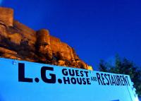 un cartel que lee la casa de huéspedes y el restaurante al lado de una montaña en L G Guest House, en Jodhpur