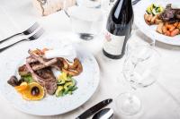 een tafel met twee borden eten en een fles wijn bij Turmhotel Gschwendt in Valle Di Casies