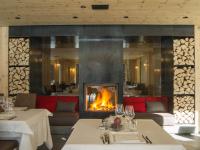 Una chimenea en un restaurante con dos mesas con copas de vino. en Hotel Spol - Adults only, en Livigno
