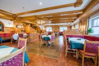 ein Restaurant mit Tischen, Stühlen und Holzdecken in der Unterkunft Hotel Grundlhof in Bramberg am Wildkogel