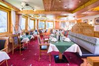 a dining room with tables and chairs and wooden ceilings at Hotel Leitner in Mittelberg