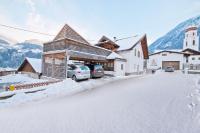 a building with cars parked outside of it in the snow at Schneggnheisl - Appartement in Sautens